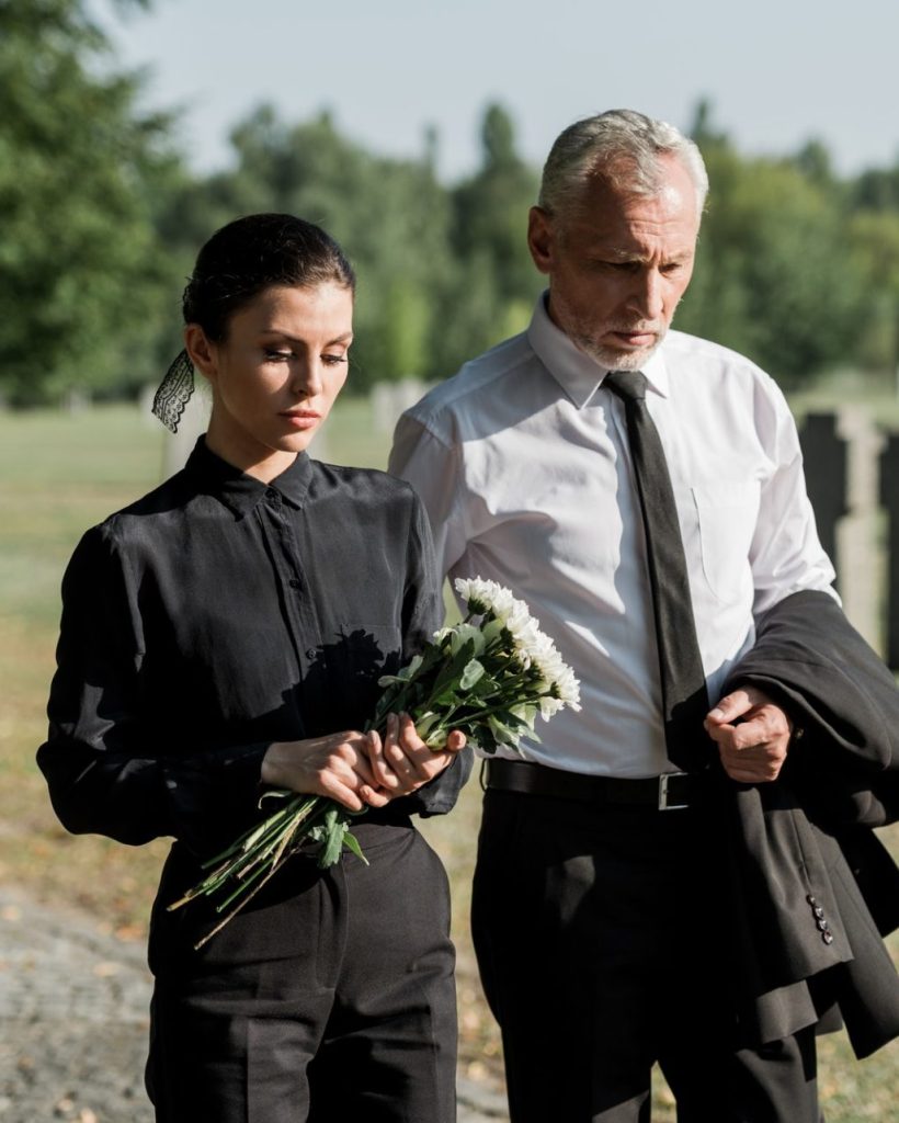 bearded-senior-man-walking-near-woman-with-flowers-on-funeral-e1636904705190.jpg